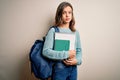 Young blonde student girl wearing backpack and books from school over isolated background with a confident expression on smart Royalty Free Stock Photo