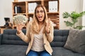 Young blonde therapist woman working at therapy office holding money celebrating victory with happy smile and winner expression Royalty Free Stock Photo