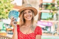 Young blonde tourist woman wearing summer style holding brazilian 100 real banknotes at the city