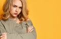 Young blonde upset girl in short blouse with crossed arms is offended much, looks angry and blame somedody.