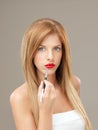 Young blonde woman applying red lipstick brush Royalty Free Stock Photo