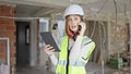 Young blonde woman architect talking on smartphone looking touchpad at construction site Royalty Free Stock Photo