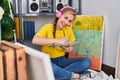 Young blonde woman artist listening to music drawing on notebook at art studio Royalty Free Stock Photo