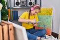 Young blonde woman artist listening to music drawing on notebook at art studio Royalty Free Stock Photo