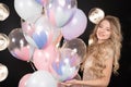 Young blonde woman with balloons on a black background in pink dress, celebrating birthday or party, beautiful girl Royalty Free Stock Photo