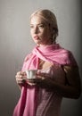 Young blonde woman behind glass with water drops. beautiful girl drinks coffee or tea Royalty Free Stock Photo