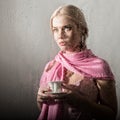 Young blonde woman behind glass with water drops. beautiful girl drinks coffee or tea Royalty Free Stock Photo