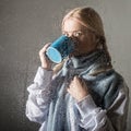 Young blonde woman behind glass with water drops. beautiful girl drinks coffee or tea Royalty Free Stock Photo