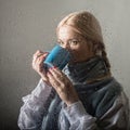 Young blonde woman behind glass with water drops. beautiful girl drinks coffee or tea Royalty Free Stock Photo