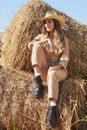 Young blonde woman in a beige jumpsuit is sitting on the rolls of hay Royalty Free Stock Photo