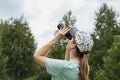 Young blonde woman bird watcher in cap and blue t-shirt looking through binoculars at cloudy sky in summer forest ornithological Royalty Free Stock Photo