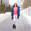 Young blonde woman in blue down jacket in winter street