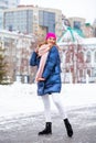 Young blonde woman in blue down jacket in winter street