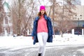 Young blonde woman in blue down jacket in winter street