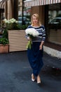 Young blonde woman in blue dress with peonies bouquet Royalty Free Stock Photo