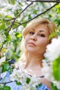 A young blonde woman in a blue dress in a spring blooming garden. The concept of a plus-size woman and tenderness, modern beauty Royalty Free Stock Photo