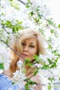 A young blonde woman in a blue dress in a spring blooming garden. The concept of a plus-size woman and tenderness, modern beauty Royalty Free Stock Photo