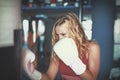 Young blonde woman boxing to heavy bag in gym cinematic