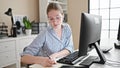 Young blonde woman business worker using computer and earphones taking notes at office Royalty Free Stock Photo