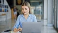 Young blonde woman business worker using laptop and earphones taking notes at office Royalty Free Stock Photo