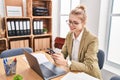 Young blonde woman business worker using laptop and smartphone at office Royalty Free Stock Photo