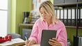 Young blonde woman business worker using touchpad taking notes at office Royalty Free Stock Photo