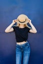 Young blonde woman in casual black t shirt and hat against blue metal background outdoor in city t shirt mock up