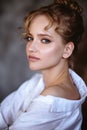 Young blonde woman in a casual white shirt and jeans in a loft interior, close up fashion portrait