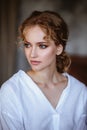 Young blonde woman in a casual white shirt and jeans in a loft interior, close up fashion portrait