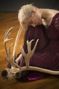 Young blonde woman crouching among caribou antlers in the studio