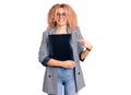 Young blonde woman with curly hair holding business folder smiling happy pointing with hand and finger Royalty Free Stock Photo