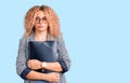 Young blonde woman with curly hair holding business folder thinking attitude and sober expression looking self confident Royalty Free Stock Photo