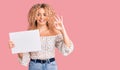 Young blonde woman with curly hair holding sale poster doing ok sign with fingers, smiling friendly gesturing excellent symbol Royalty Free Stock Photo