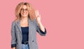 Young blonde woman with curly hair wearing business jacket and glasses showing and pointing up with fingers number three while Royalty Free Stock Photo