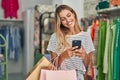 Young blonde woman customer smiling confident using smartphone at clothing store