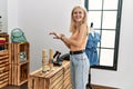 Young blonde woman customer wearing bracelet smiling at clothing store