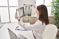 Young blonde woman doctor looking xray sitting on table at clinic Royalty Free Stock Photo