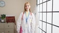 Young blonde woman doctor smiling confident holding clipboard at clinic Royalty Free Stock Photo