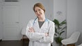 Young blonde woman doctor smiling confident standing with arms crossed gesture at clinic waiting room Royalty Free Stock Photo