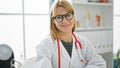 Young blonde woman doctor smiling confident wearing glasses at clinic Royalty Free Stock Photo