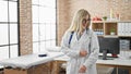 Young blonde woman doctor throwing documents dancing at clinic Royalty Free Stock Photo