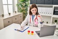 Young blonde woman doctor writing medical report holding empty test tube at clinic Royalty Free Stock Photo