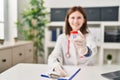 Young blonde woman doctor writing medical report holding empty test tube at clinic Royalty Free Stock Photo