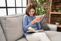 Young blonde woman drinking coffee reading book at home Royalty Free Stock Photo