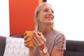 Young blonde woman drinking coffee sitting on sofa at home Royalty Free Stock Photo