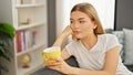 Young blonde woman drinking coffee sitting on sofa at home Royalty Free Stock Photo