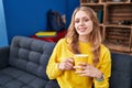 Young blonde woman drinking coffee sitting on sofa at street Royalty Free Stock Photo