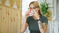 Young blonde woman drinking coffee sitting on table at coffee shop Royalty Free Stock Photo