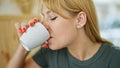 Young blonde woman drinking coffee sitting on table at coffee shop Royalty Free Stock Photo