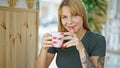 Young blonde woman drinking coffee sitting on table at coffee shop Royalty Free Stock Photo